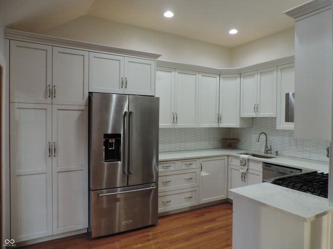 kitchen with wood flooring, a sink, light stone counters, high quality fridge, and decorative backsplash | Image 7
