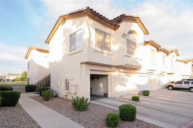 Mediterranean / spanish-style condo featuring a tiled roof, stucco siding, a detached garage and private driveway. | Image 5