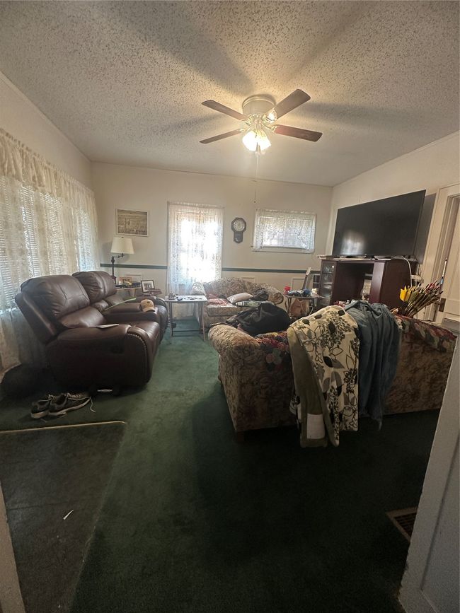 Living room with carpet, ceiling fan, and a textured ceiling | Image 5