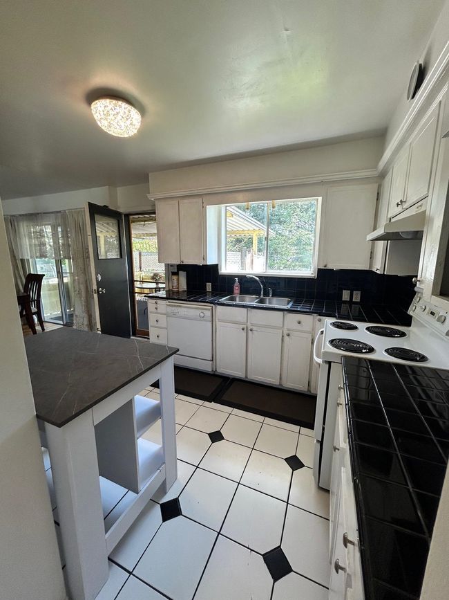 Kitchen featuring a sink, decorative backsplash, under cabinet range hood, and white appliances | Image 9