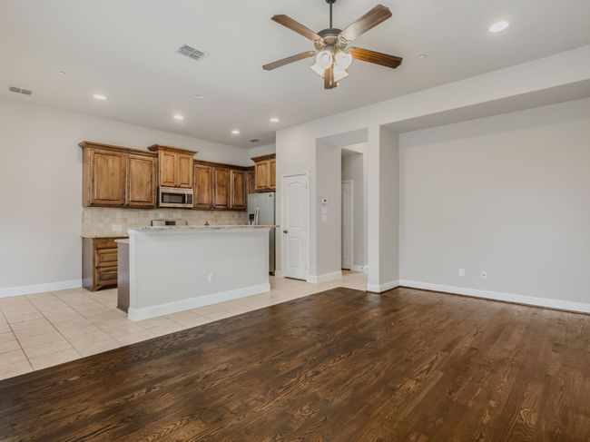 Kitchen with a ceiling fan, recessed lighting, brown cabinets, decorative backsplash, and light wood-style flooring | Image 10