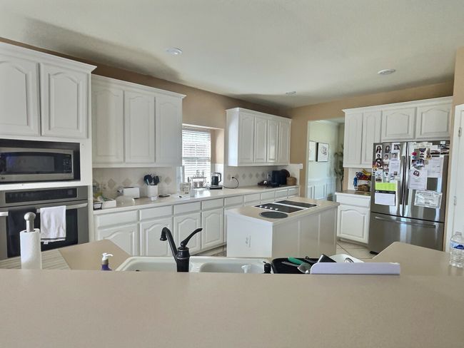 Kitchen featuring stainless steel appliances, tasteful backsplash, white cabinets, a sink, and recessed lighting | Image 7