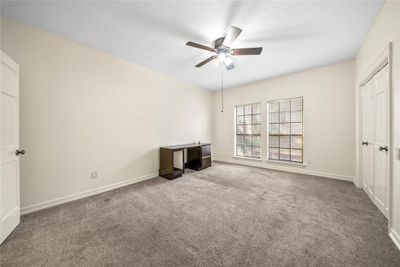 Primary bedroom featuring carpet floors, ceiling fan, walk in closet and ensuite bathroom | Image 3