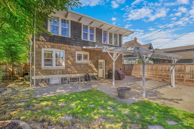 Rear view of property featuring a pergola, a patio, a fenced backyard, and stone siding | Image 47