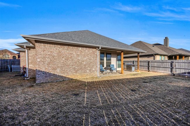 Rear view of house with a patio, a fenced backyard, brick siding, and a shingled roof | Image 29