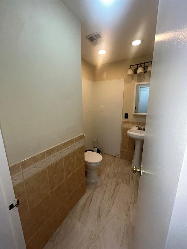 Half bathroom featuring tile walls and wainscoting | Image 8