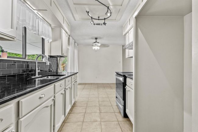 The kitchen offers ample storage with upper and lower cabinets plus a custom walk-in pantry for bulk items and small appliances. | Image 13