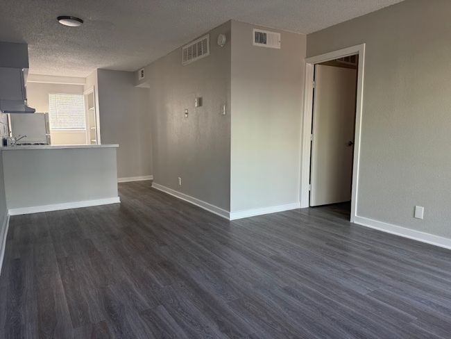 Unfurnished living room featuring a textured ceiling, dark wood-type flooring, and baseboards | Image 4