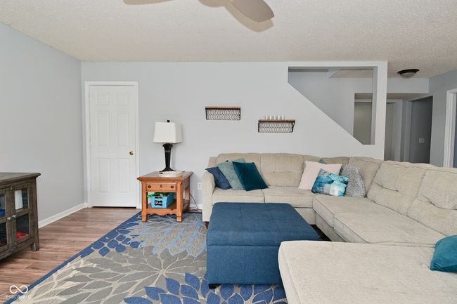 living room featuring wood finished floors, ceiling fan, a textured ceiling, and baseboards | Image 9