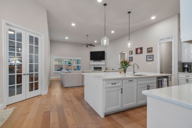 Kitchen featuring ceiling fan, french doors, light wood-style floors, white cabinets, and a sink | Image 8