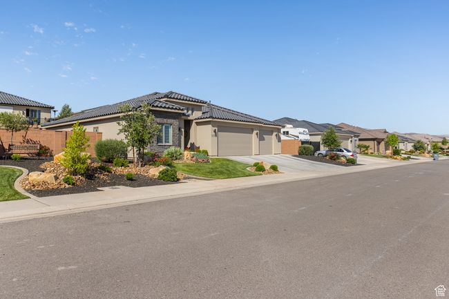 View of front of property featuring a garage, concrete driveway, stucco siding, a tile roof, and a residential view | Image 61
