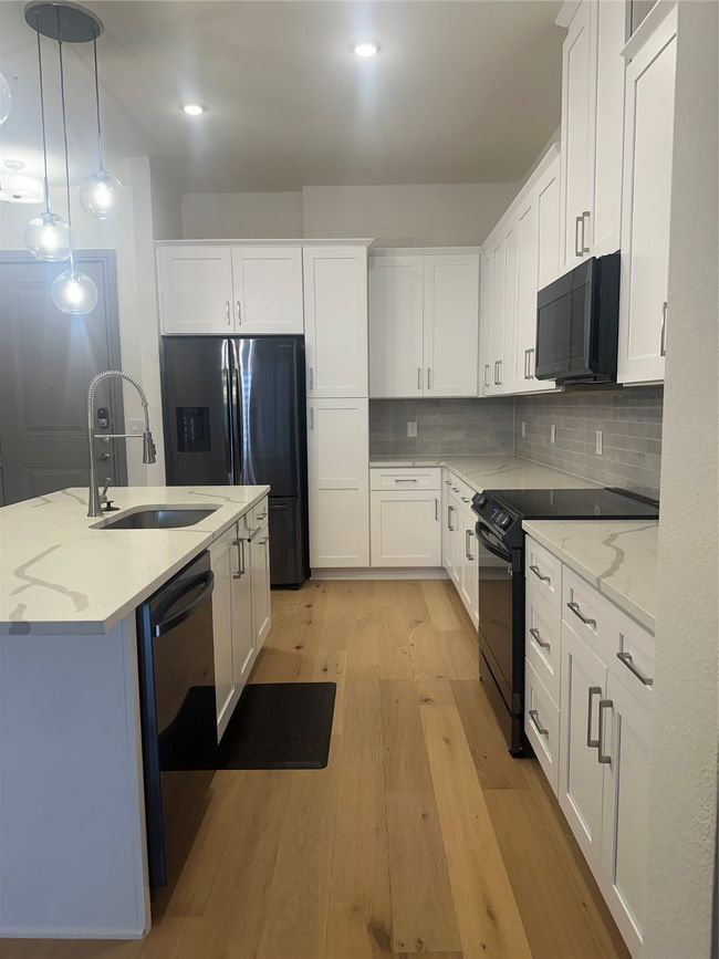 Kitchen with range, dishwashing machine, refrigerator, light wood-style floors, and white cabinets | Image 4