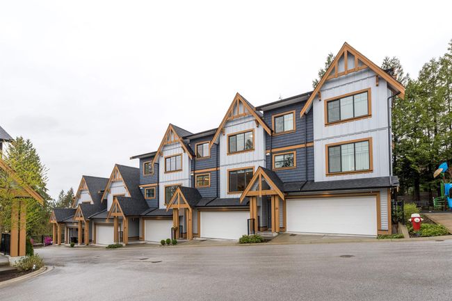 Townhome / multi-family property featuring board and batten siding, a residential view, and a garage | Image 22