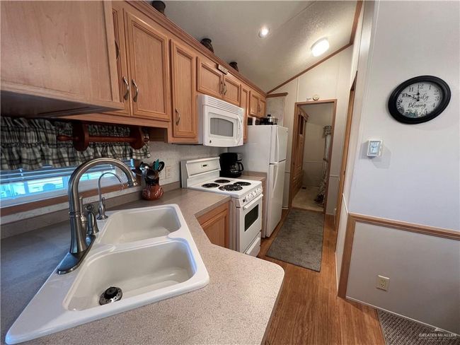 Kitchen featuring white appliances, dark wood-type flooring, lofted ceiling, and sink | Image 6