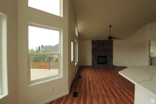 Unfurnished living room featuring a ceiling fan, a fireplace, dark wood-style floors, and high vaulted ceiling | Image 5