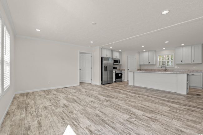 Unfurnished living room with crown molding, light wood-style flooring, recessed lighting, and baseboards | Image 6