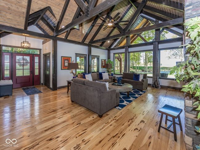 living area with high vaulted ceiling, hardwood / wood-style floors, baseboards, and wood ceiling with exposed beams | Image 7