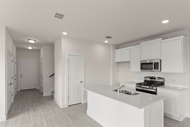 Kitchen with visible vents, appliances with stainless steel finishes, tasteful backsplash, a sink, and white cabinetry | Image 12