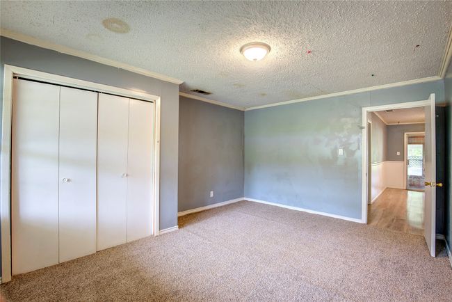 Unfurnished bedroom with crown molding, carpet flooring, a textured ceiling, a closet, and baseboards | Image 26