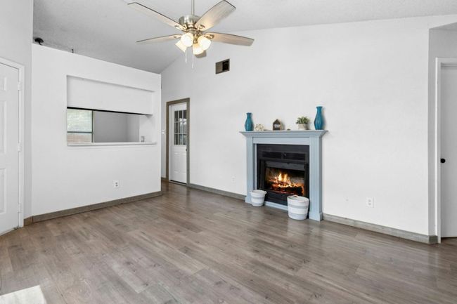 living room featuring a fireplace, light wood-style flooring, a ceiling fan, and high vaulted ceiling | Image 8
