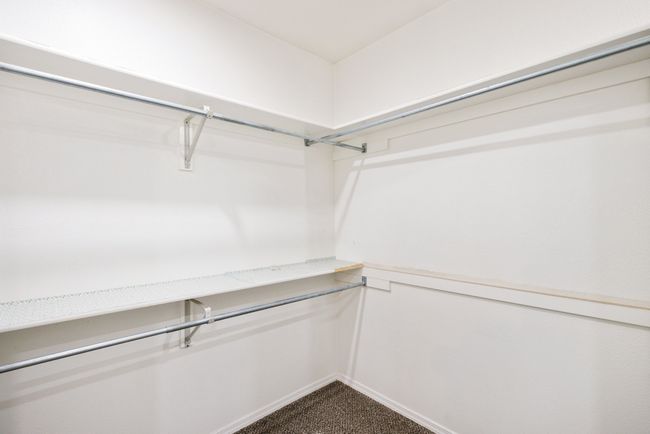 Walk in closet featuring dark colored carpet | Image 19