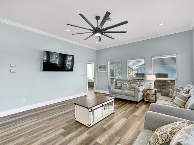 Relax in the spacious living room with a modern lighted ceiling fan, recessed lights, ample seating, and a wall-mounted TV so you can gather for movie nights or laughter and games after a day at the beach. | Image 8