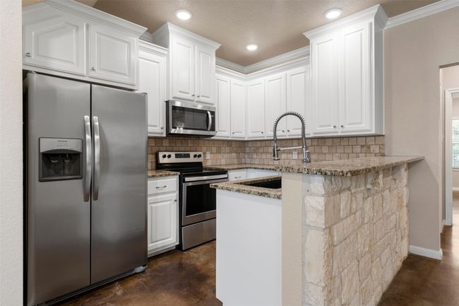 Kitchen with appliances with stainless steel finishes, finished concrete floors, tasteful backsplash, light stone countertops, and recessed lighting | Image 4