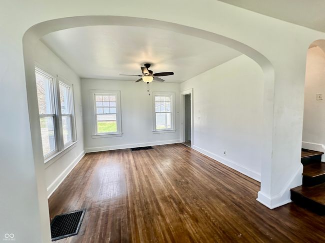 unfurnished living room with arched walkways, visible vents, and dark wood-style flooring | Image 22