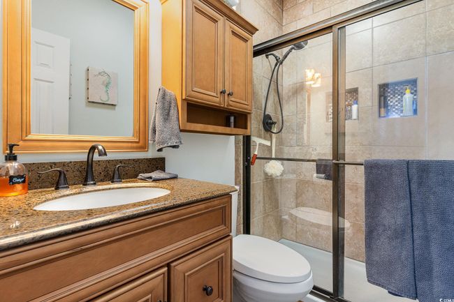 Bathroom featuring toilet, tiled shower, and vanity | Image 14