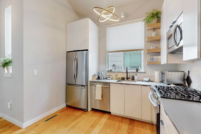 Kitchen featuring stainless steel appliances, a sink, light wood finished floors, light countertops, and open shelves | Image 14