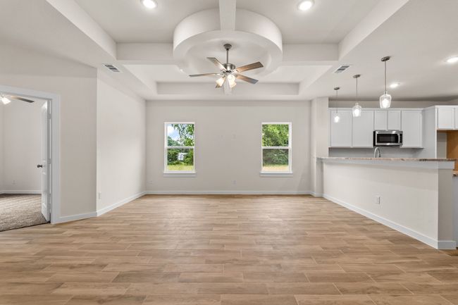 Kitchen with stainless steel microwave, ceiling fan, white cabinets, a tray ceiling, and recessed lighting | Image 8