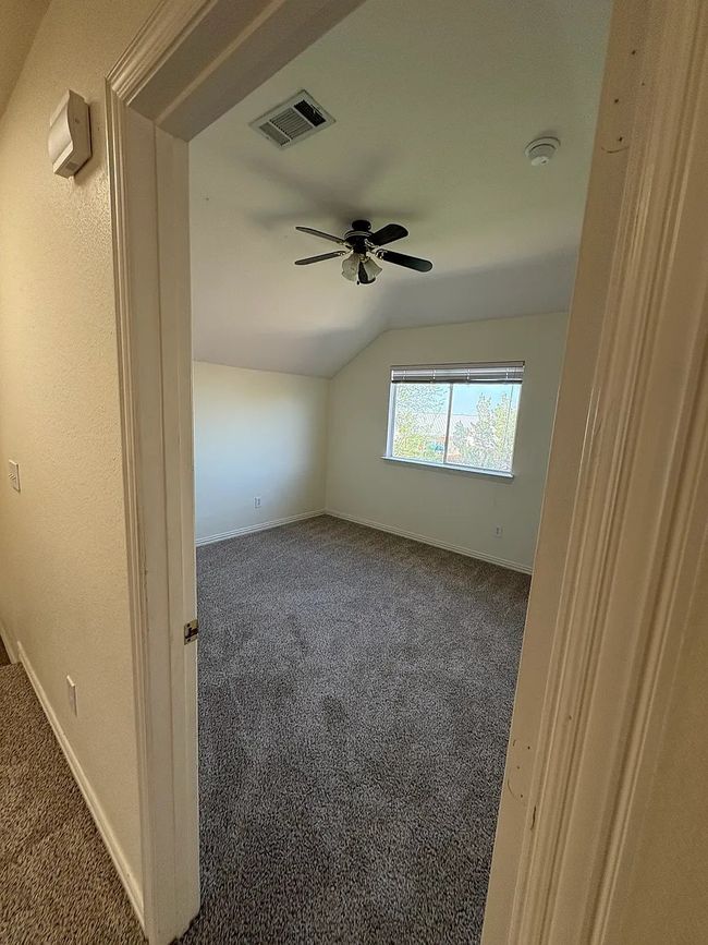 Spare room featuring dark carpet, lofted ceiling, a ceiling fan, and a smoke detector | Image 6