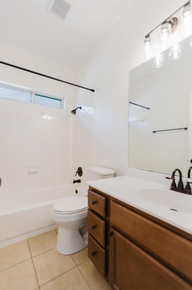 Bathroom with visible vents, toilet, washtub / shower combination, tile patterned flooring, and vanity | Image 16