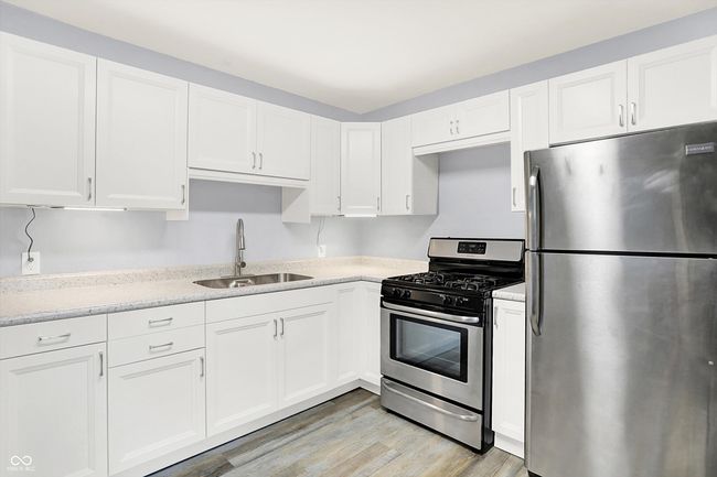 kitchen with appliances with stainless steel finishes, a sink, white cabinetry, and light wood-style flooring | Image 11