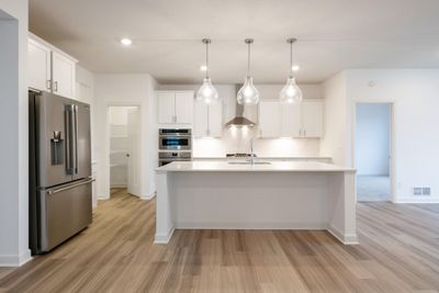 (Photo of similar home, finishes will vary)The spacious kitchen features stylish cabinetry, a walk-in pantry for added storage and an island with bar-style seating. | Image 1