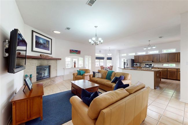 Living room featuring a chandelier, visible vents, a fireplace, and light tile patterned floors | Image 9