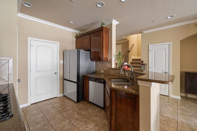 Kitchen featuring a peninsula, stainless steel dishwasher, crown molding, and a sink | Image 31