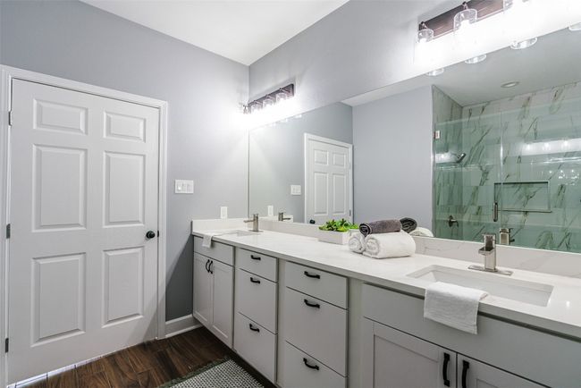 Full bathroom featuring double vanity, a marble finish shower, and wood finished floors | Image 17
