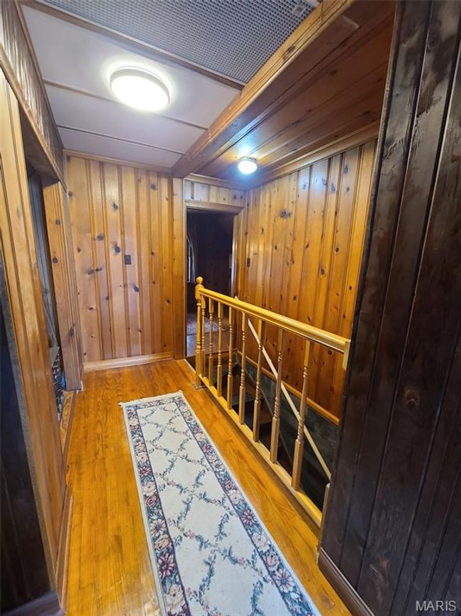 Hallway featuring an upstairs landing, wood finished floors, and wooden walls | Image 16