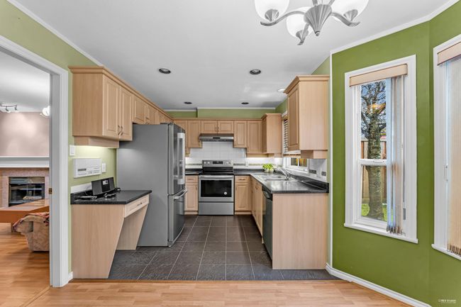 Kitchen with appliances with stainless steel finishes, a sink, light brown cabinetry, and dark countertops | Image 12