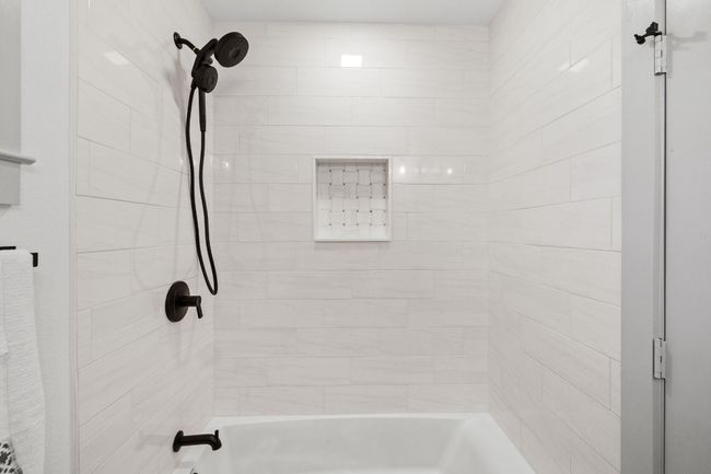 The secondary bathroom has a light gray subway tile that extends to the ceiling and a beautiful modern mosaic niche. | Image 25
