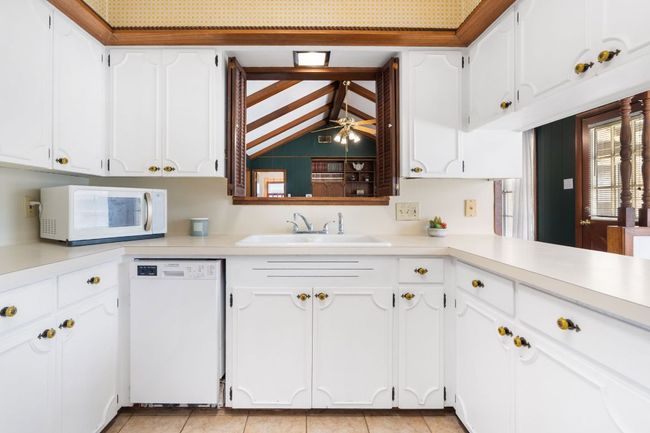Kitchen featuring white appliances, kitchen pass-through with original shutters, light countertops, and white cabinetry | Image 10