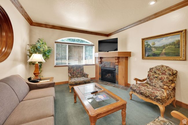 Carpeted living area with baseboards, a fireplace, and crown molding | Image 12