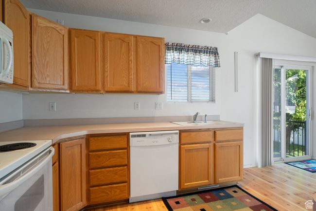 Kitchen featuring white appliances, light wood-style floors, light countertops, healthy amount of natural light, and a textured ceiling | Image 11