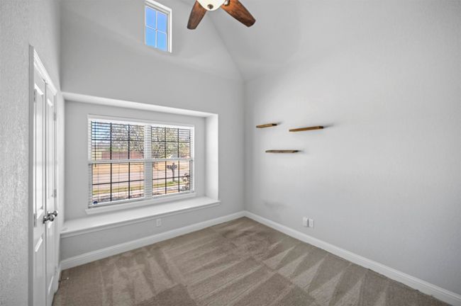 Carpeted empty room featuring baseboards, high vaulted ceiling, and a ceiling fan | Image 4
