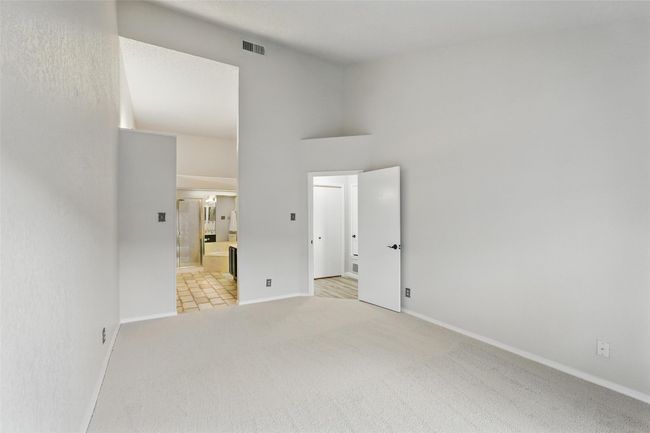 Unfurnished bedroom featuring new carpet, ensuite bath, and a towering ceiling | Image 11