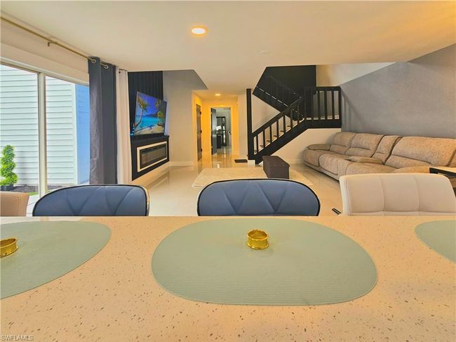 Living area with recessed lighting, a glass covered fireplace, and stairs | Image 13