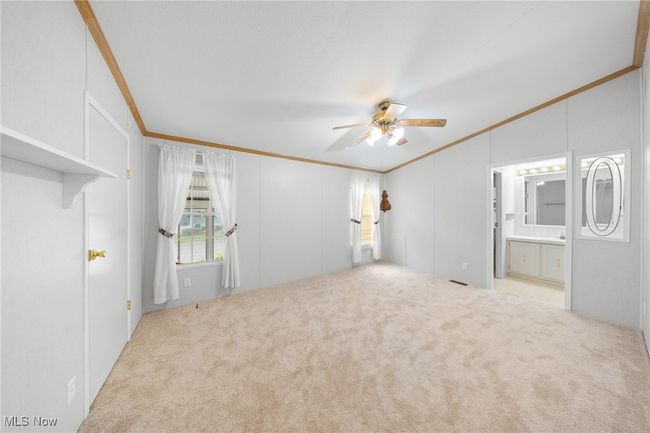 Carpeted empty room featuring ornamental molding, vaulted ceiling, and ceiling fan | Image 10
