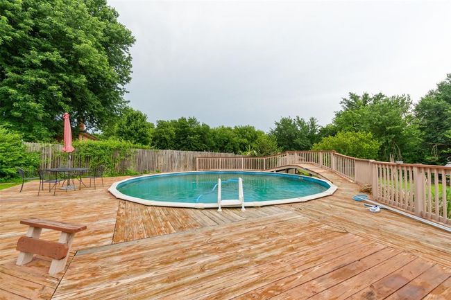View of swimming pool featuring a wooden deck and view of scattered trees | Image 34