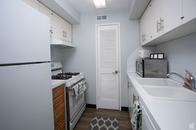 Kitchen featuring white cabinetry, sink, dark hardwood / wood-style flooring, and white appliances | Image 3